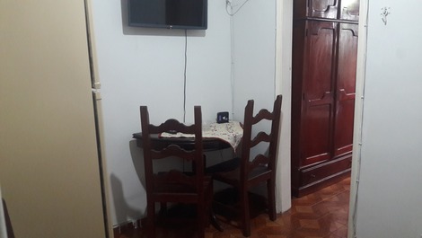 Sala: geladeira duplex, mesa com 3 cadeiras, tv no suporte, sofá-cama e  1 ventilador de teto 