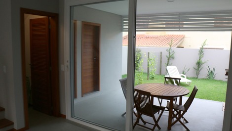 Varanda nos fundos com churrasqueira, mesa e pátio fechado