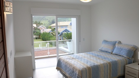 Suíte principal com cama box de casal e sacada com vista para serra