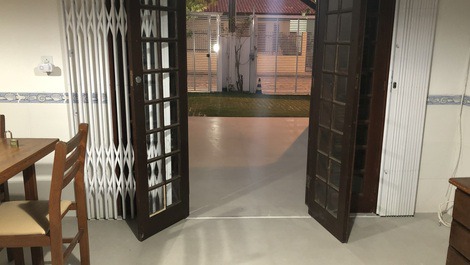 Entrada da sala de estar da casa 1, com porta pantográfica e ar-condicionado.