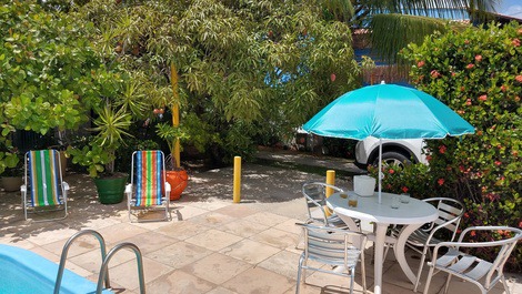 Visão do deck da piscina. Bastante arborizado. Com conj. mesa e cadeiras, 10 cadeiras de praia