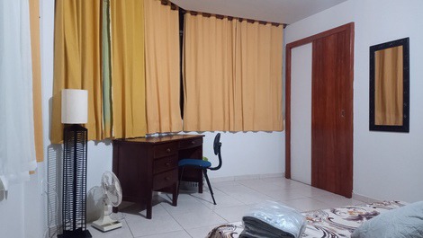 Mesa, abajur, ventilador ainda no quarto.