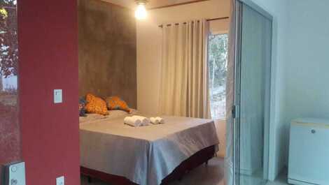 Quarto com ar condicionado, ventilador e cama queen