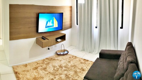 Sala de estar espaçosa com sofá retrátil e smart tv.