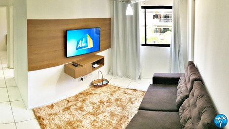 Sala de estar espaçosa com sofá retrátil e smart tv.