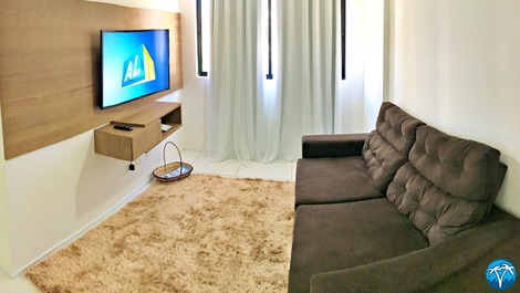 Sala de estar espaçosa com sofá retrátil e smart tv.