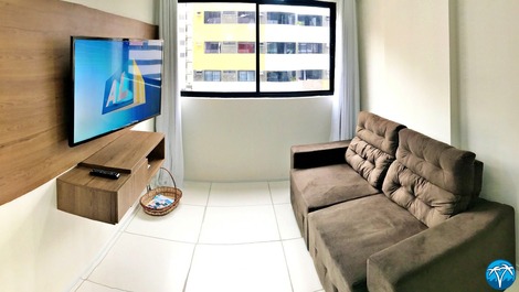 Sala de estar espaçosa com sofá retrátil e smart tv.