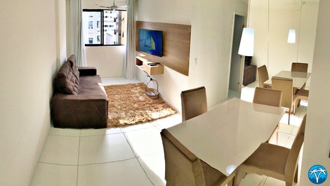 Sala de estar espaçosa com sofá retrátil e smart tv.