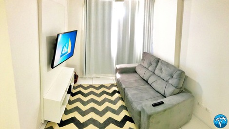 Sala de estar espaçosa com sofá retrátil e smart tv.