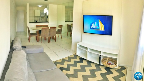 Sala de estar espaçosa com sofá retrátil e smart tv.