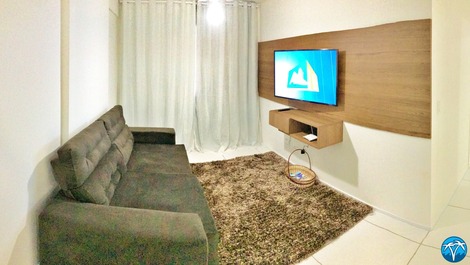 Sala de estar espaçosa com sofá retrátil e smart tv.