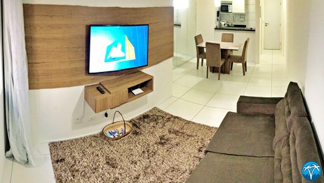 Sala de estar espaçosa com sofá retrátil e smart tv.