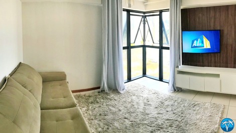 Sala de estar espaçosa com sofá retrátil e smart tv.