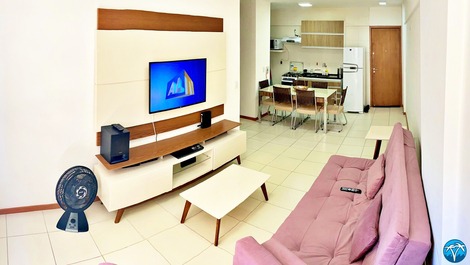 Sala de estar espaçosa com sofá retrátil e smart tv.