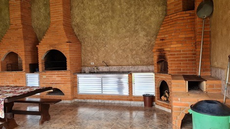 Espaço goumert com churrasqueira tradicional e para espetos, forno a lenha e fogao a lenha