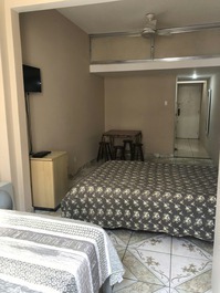 Cama de casal e mesa com quatro bancos
