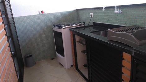 Fogão, geladeira, armários da área da churrasqueira.