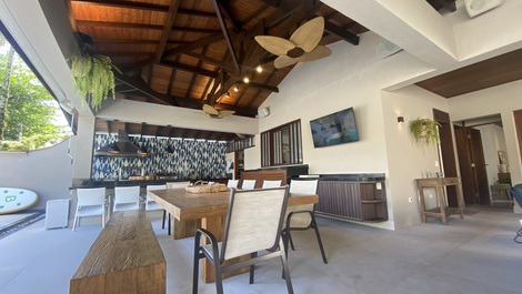 Mesa de jantar externa com 12 lugares e balcão da churrasqueira com 6 lugares