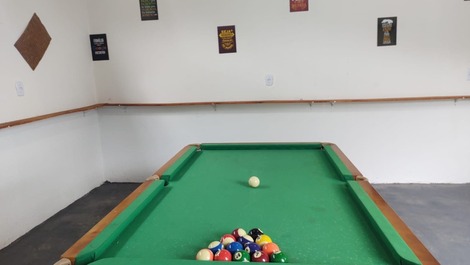 Salão de jogos com mesa de sinuca, totó e mesa de botão de futebol