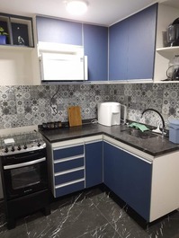 A outra parte da cozinha com fogão, micro-ondas, purificador de água, eletros e utensílios no armári