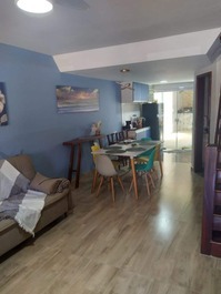 Estar, com ventilador de teto, jantar e cozinha ao fundo.