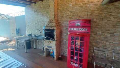 Area de churrasqueira com mesa e bancos e freezer