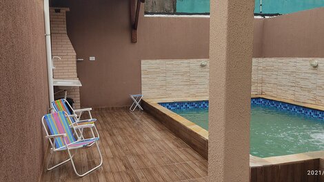 Piscina com churrasqueira aí lado cadeiras e mesa de apoio 