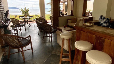 Vista do bar, com sala de estar, lareira, mesa de jogos e vista para o mar