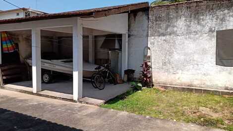 Área com churrasqueira, mesa e gramado nos fundos da casa.