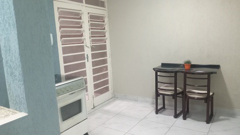 Mesa de refeições com 2 cadeiras e porta dupla da entrada do imóvel 