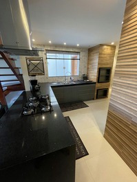 Cozinha com cook top, ampla bancada e churrasqueira 