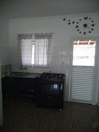 Cozinha com utencílios, fogão de 5 bocas e geladeira com freezer.