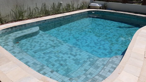 Moderniza o a piscina de dia verde e a noite iluminada de azul