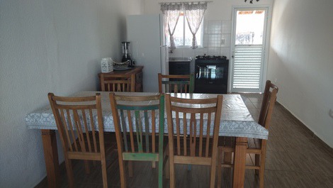 Mesa de jantar, cozinha e porta para o quintal dos fundos.