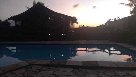 Fachada noturna da casa vista da piscina