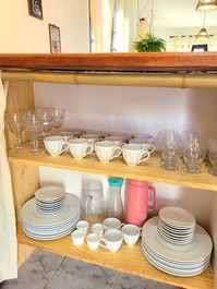Cozinha equipada com pratos, copos, taças, xícaras, panelas, talheres