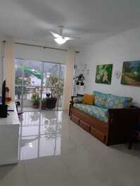 Sala principal e varanda com sofá cama e vista para natureza