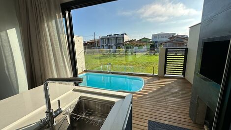 Piscina, churrasqueira, deck e portão de acesso ao gramado.