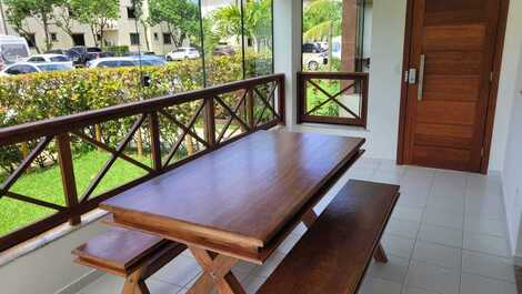 Varanda com fechamento em vidros, persianas blackout e mesa em madeira angelin com bancos.