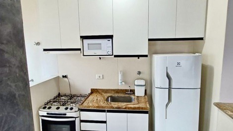 Cozinha com armários novos e conta com torneira com filtro, microondas, tostequeira, garrafa de café, panelas e utensílios em geral 