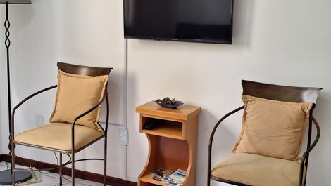 Televisão, cadeiras ornamentais, rack e abajur.