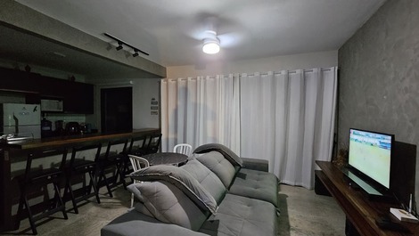 Sala de tv integrada com bancada da cozinha e área de lazer.