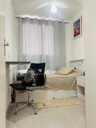 Quarto com cama de solteiro e cama auxiliar, com guarda roupa e ventilador de teto.