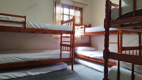 O quarto com ventilador com três beliches mais três colchões avulsos todos com roupa de cama lençol 