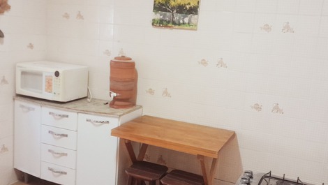 Cozinha com armário, micro ondas, filtro para água, e mesa para café.