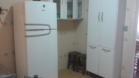 Cozinha com geladeira e armários com utensílios.