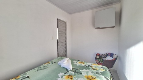 Quarto com cama de casal, ar condicionado, cadeira, armário aéreo e blackout
