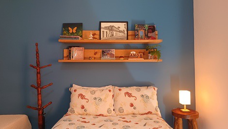 Cama, estante de livros, cabideiro e luminária de luz amarela