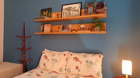 Cama, estante de livros, cabideiro e luminária de luz amarela