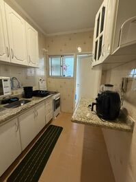 Cozinha com fogão, microondas, geladeira, airfryer, sanduicheira, liquidificador e armários com todos utensílios.